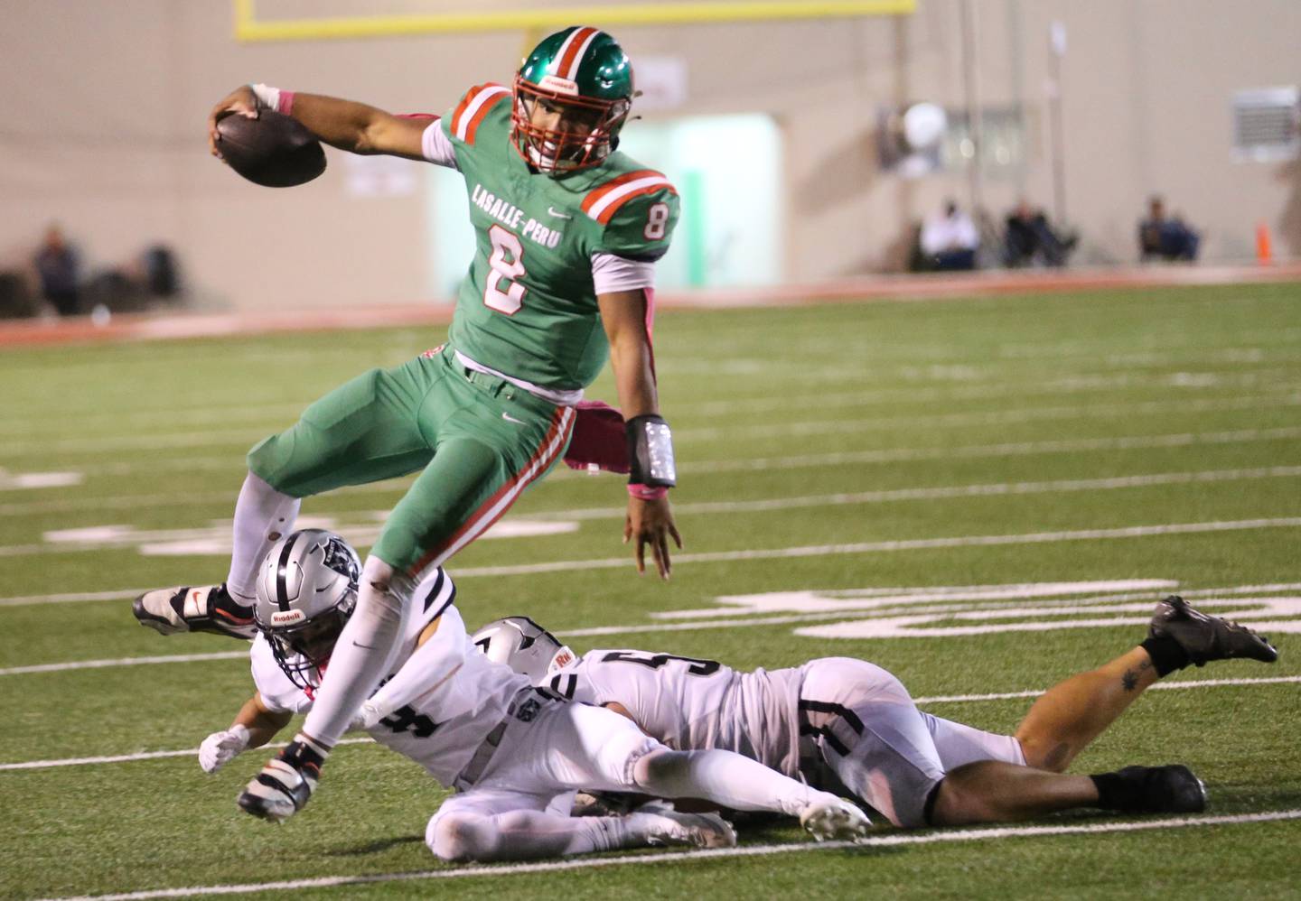 L-P quarterback Marion Persich hurdles Kaneland defenders Alex Alvarez and Jack Koller on Friday, Oct. 17, 2025 at Howard Fellows Stadium.