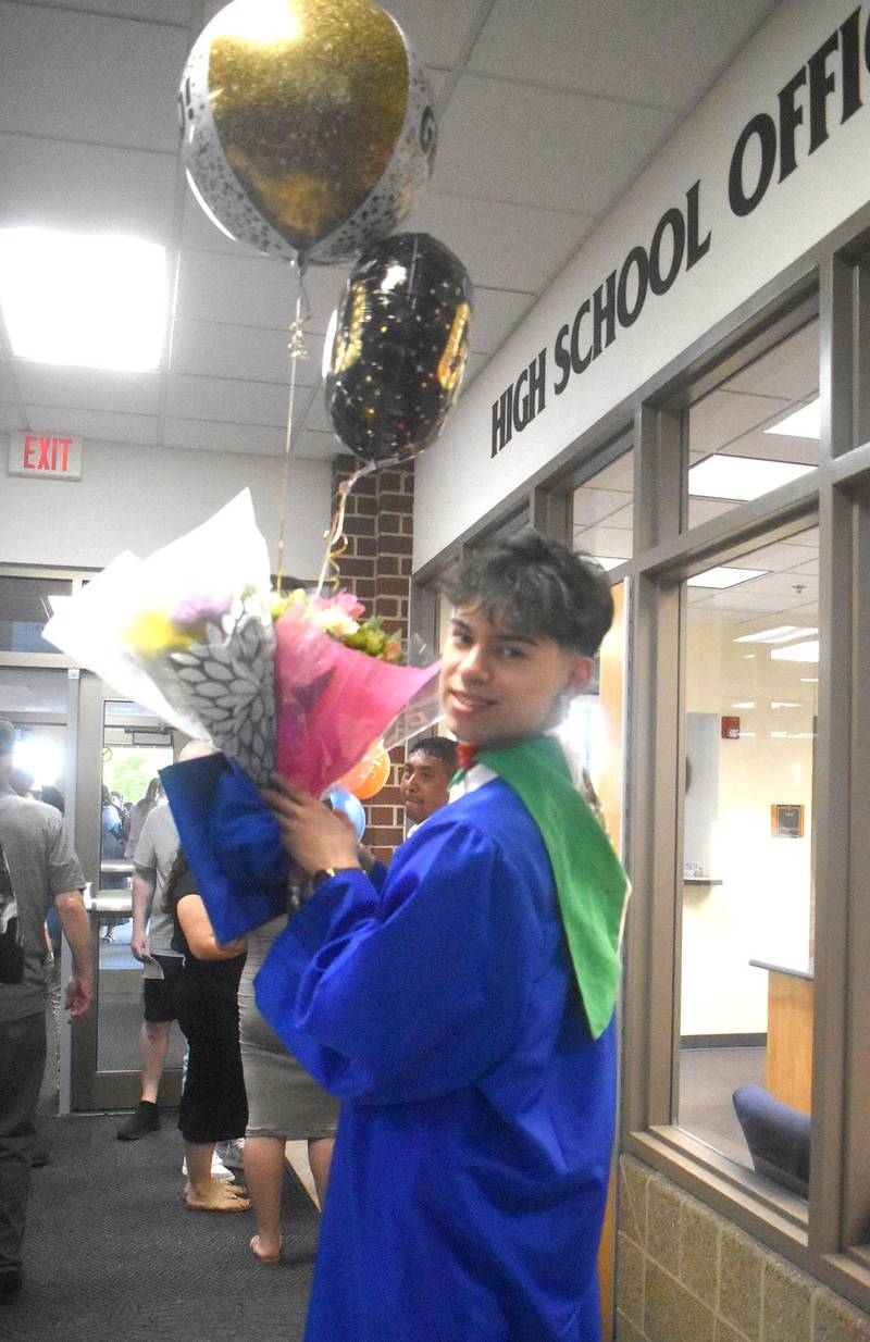 Graduate Javier Pizano carries balloons and flowers he received from his family after the commencement ceremony Saturday, May 20, 2023, at Genoa-Kingston High School.
