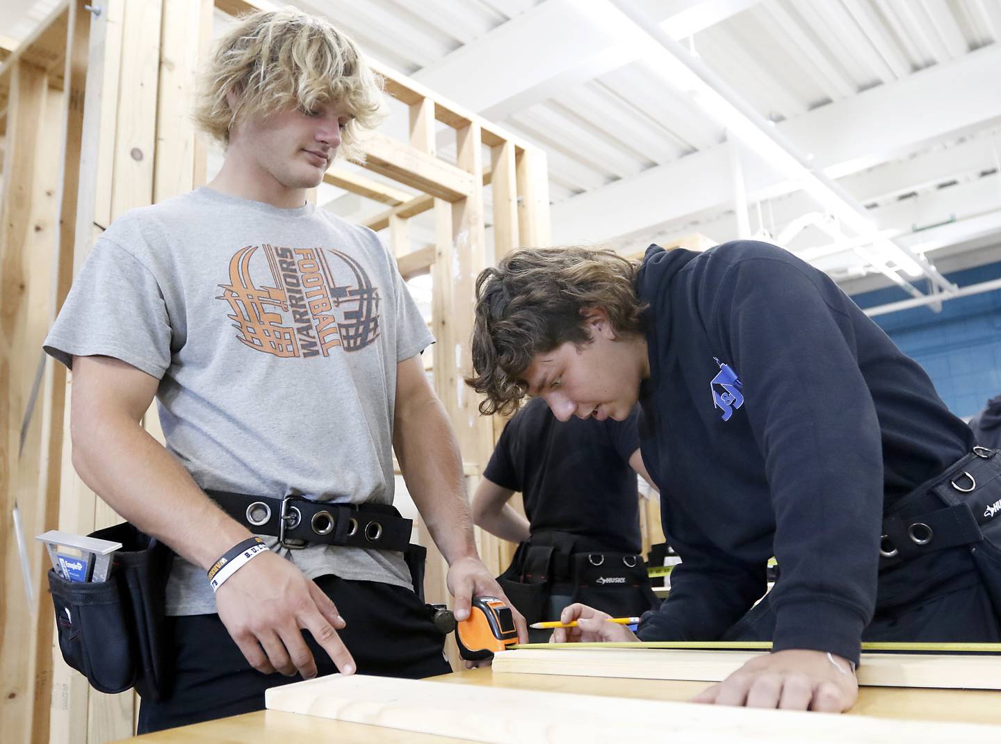 McHenry High School seniors Frank Smiesko, left, and Carlo Alfaro, right, measure a plank to build a stud wall Tuesday, Aug. 30, 2022, during a building trades class at the school McHenry secondary.  Students in the class will build the tiny stores that will house the incubator retail businesses on McHenry's Riverwalk in Miller Point.