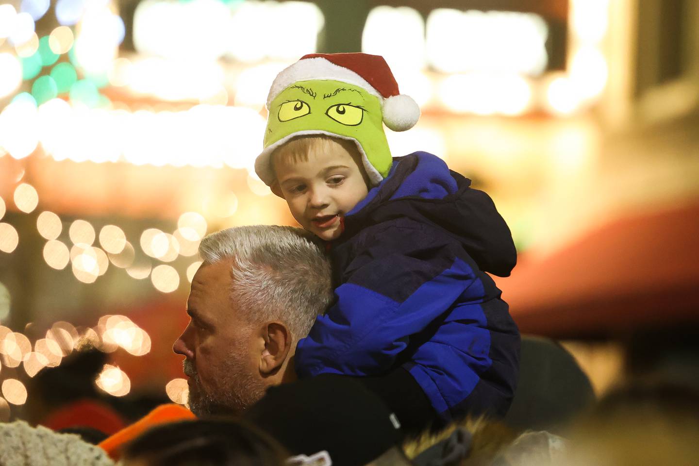 Brian Bessler Jr. sits on his father Brian’s shoulders for an unobstructed view of the parade at the Light Up the Holidays Festival and Parade in downtown Joliet.