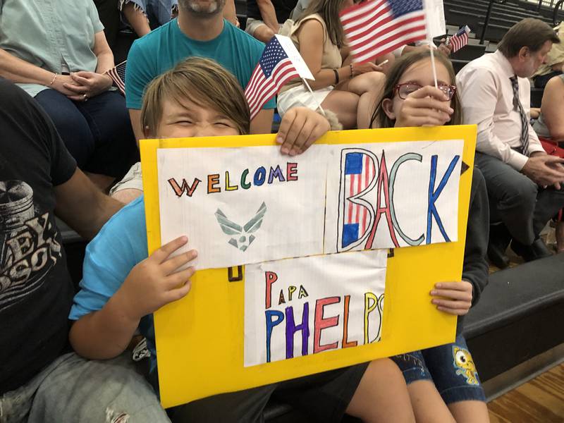 Jude Phelps, 9, of Ringwood, and Allison Krenke, 10, of Madison, Wisconsin, hold up a sign welcoming back their grandfather, Barry Phelps, at the Honor Flight Ceremony Aug. 27.