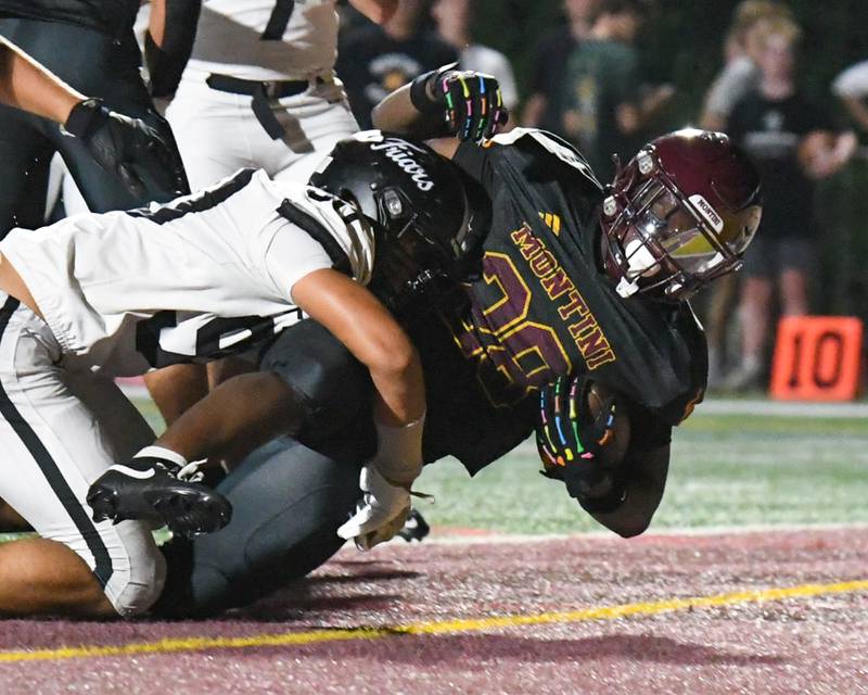 Montini Catholic’s Isaac Alexander (28) gets brought down by Fenwick's Zikomo Mbewe (90) in the endzone after scoring a touchdown during the game on Friday Sept. 19, 2025, held at Montini Catholic High School.