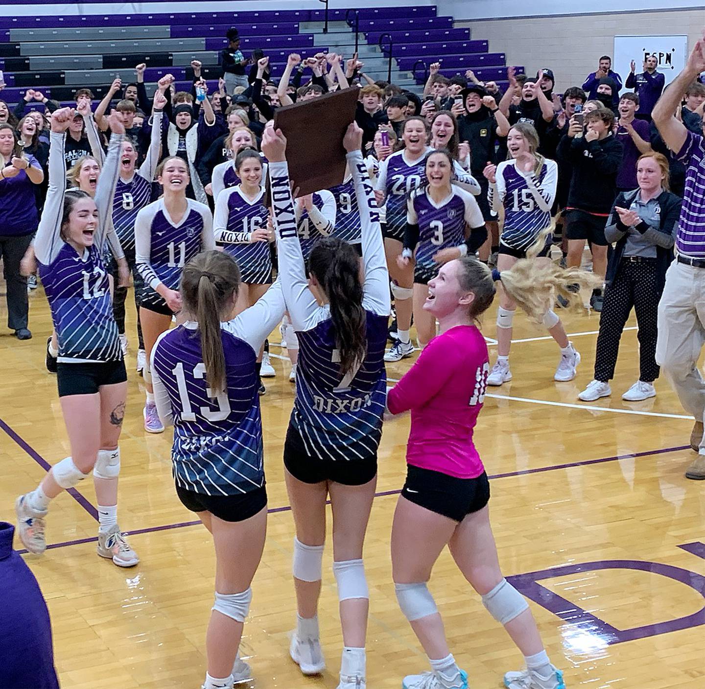 Dixon's Hanna Lengquist (13), Sydney Hargrave (7) and Natalie Davidson hold up the plaque to their teammates after winning the Class 3A Dixon Regional championship over Galesburg on Thursday night at Lancaster Gym.