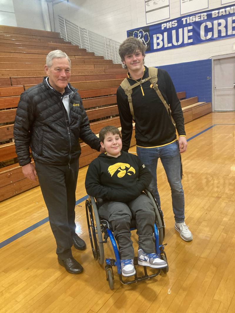 Iowa Hawkeye football coach Kirk Ferentz and recruit Teegan Davis visit with Tiger fan Zane Britton atTuesday's Princeton basketball game.