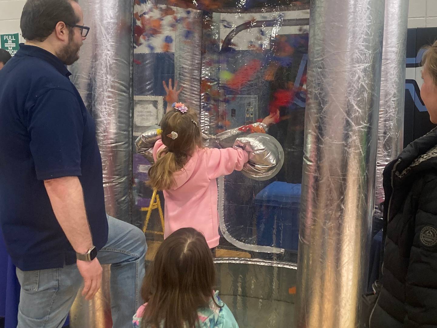Karianne Jilek tries to grab papers in a wind machine to win a prize from the Will County Emergency Management Agency booth at the Will County Kids Fair at Troy Middle School in Plainfield on Monday, Feb. 17, 2025.