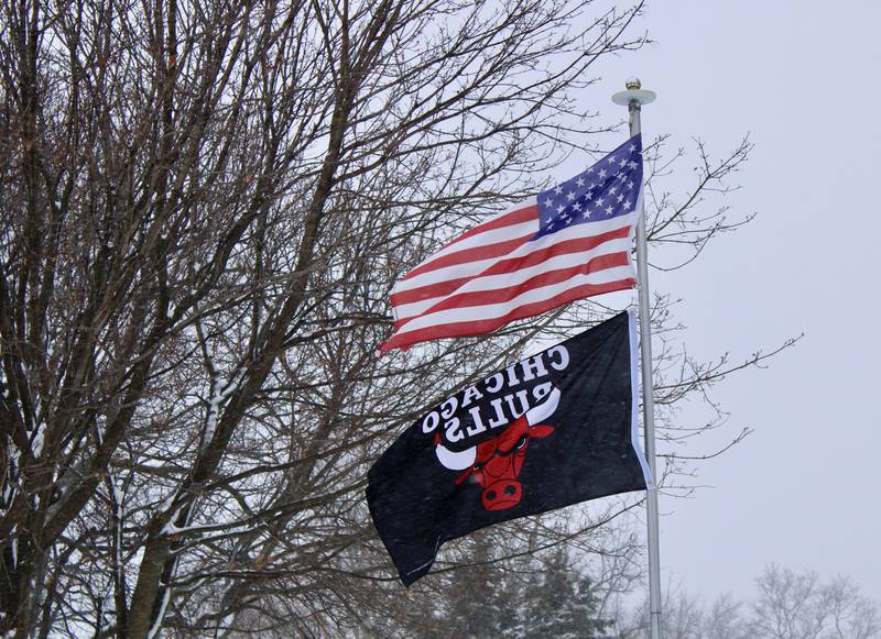 A United States flag and a Chicago Bulls banner flap in the gusting wind from a flagpole at the end of East Harrison Street in Granville on Saturday at the height of the snowstorm.