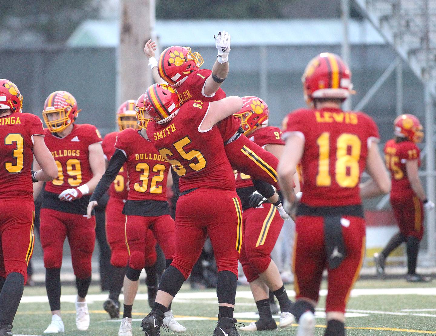 Batavia's Jon Smith (65) lifts up teammate Trey Urwiler in celebration of a touchdown during a game against St. Charles North at Batavia on Friday, March 26, 2021.