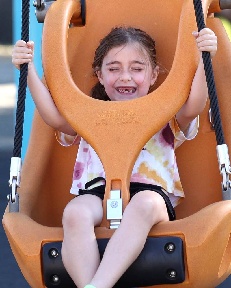 Ripley Ostrom, 6, from DeKalb, rides the zipline Friday, June 14, 2024, at the new playground at Hopkins Park during a Dedication Celebration event for the grand opening of the new playground and racquet courts.
