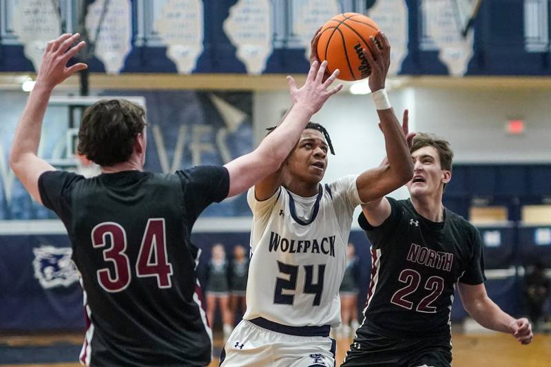 Oswego East's Mason Lockett IV (24) drives to the hoop against Plainfield North's Quintin Wiencek (34) and Samuel Finn (22) during a basketball game at Oswego East High School on Friday, Dec. 6, 2024.