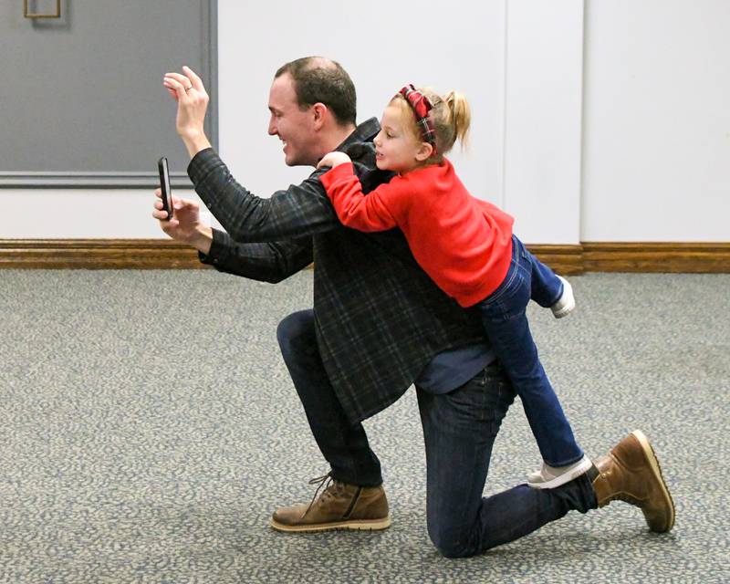 Nora Murphy, 3, tries to help her dad Kevin Murphy of La Grange make their family friends smile as they pose for a photo during the breakfast with Santa event held on Sunday Dec. 15, 2024, held at the La Grange Park District Recreation Center.