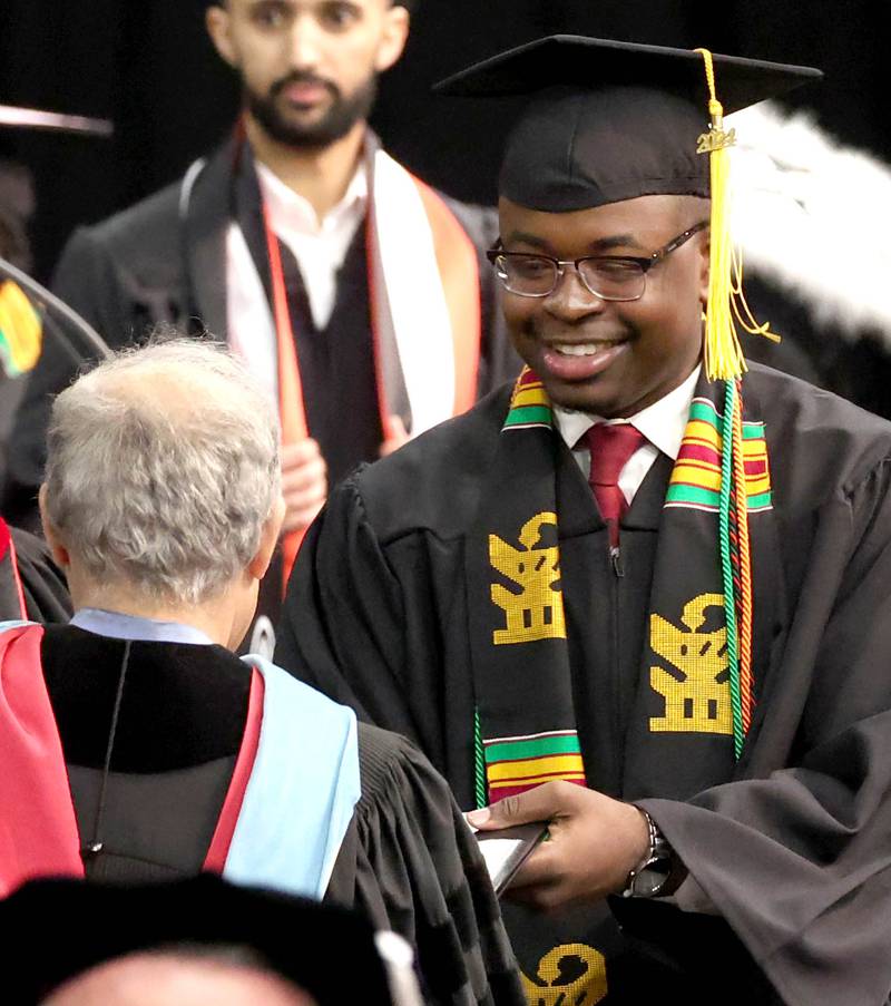 A Northern Illinois University graduate receives his diploma during the first of two undergraduate commencement ceremonies Saturday, May 11, 2024, in the Convocation Center at NIU in DeKalb.