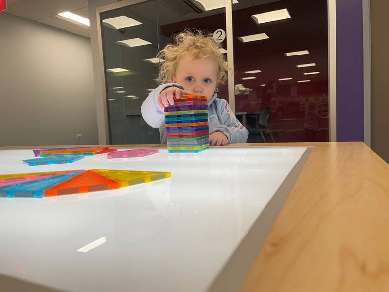 Rayna Haun, 2, of Algonquin, plays at the Algonquin Public Library's Eastgate branch's library's newly added light-up magnetic tile table the day a $6 million renovation of the branch opened on Jan. 6, 2025.