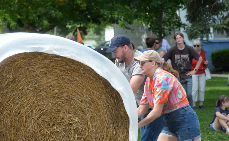 Joe and Jess Novak give it their all as they roll a large round straw bale down Wesley Avenue in Mt. Morris during the Straw Bale Race at Strawfest on Saturday, Aug. 23, 2025. The team with the fastest time won the event. Joe and Jess were visiting from California and agreed to give it a try, posting a time of 11 seconds.