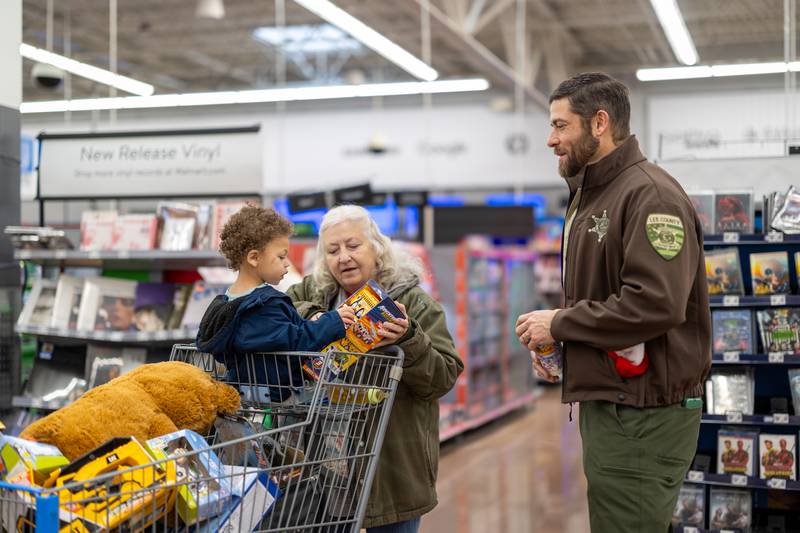 A 2-year-old shopper and his grandma hang out with Lee County officer Matt Frye during Shop with a Cop on Saturday, December 14, 2024. Roughly 37 kids participated in the morning session of this annual holiday event.