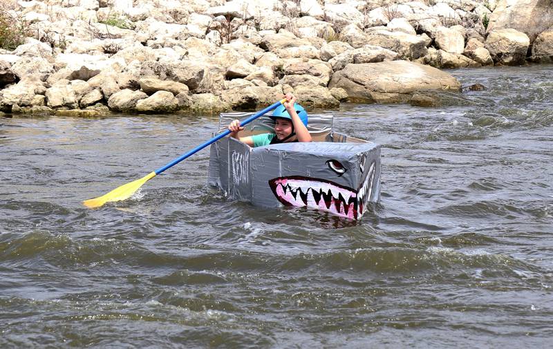 A participant of the cardboard boat race paddles down the Fox River at Yorkville River Fest on Saturday, July 19, 2025.