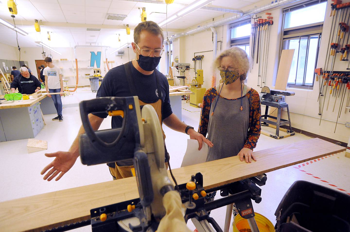 Teacher Brett Fankhauser shows junior Reanna Garrett, 17, where she should cut a piece of wood as he teaches students Wednesday, March 23, 2022, in a wood shop class at Woodstock North High School. The students are making end tables. Fankhauser also teaches at Woodstock High School.