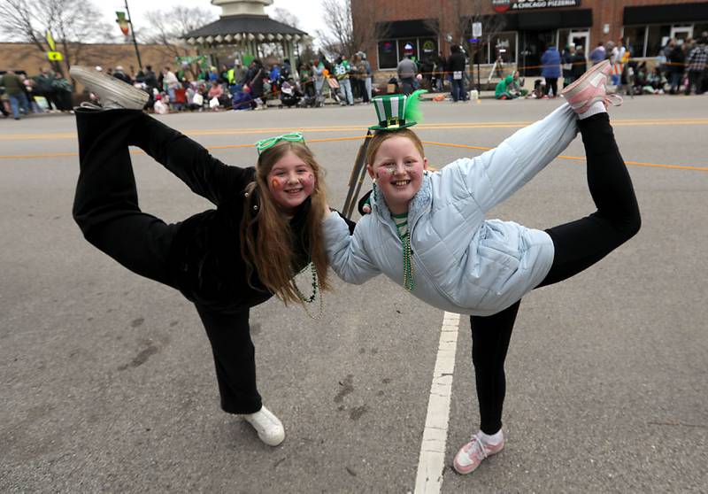 Friends Alaina Lemaire and Makayla Mahon practice a cheerleading routine while waiting for the McHenry ShamROCKS the Fox Festival Parade to start on Saturday, March 14, 2026. In McHenry.