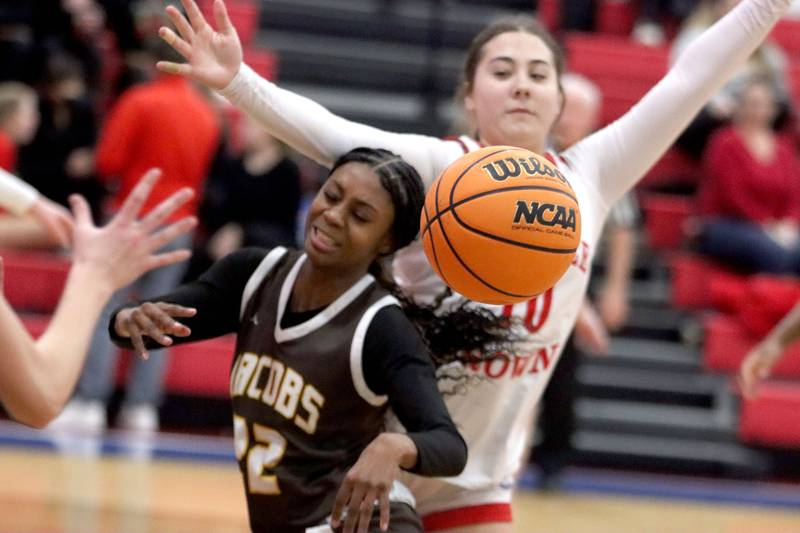 Jacobs’ Bri Ramsey, left, passes the ball as she gets past Dundee-Crown’s Kate Graham in varsity girls basketball on Friday, Dec. 12, 2025, at Dundee-Crown High School in Carpentersville.