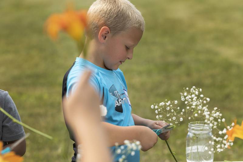 Emmett trims the stem on a bouquet Thursday, June 29, 2023 during the Whiteside County Farm Bureau’s camp at Woodlawn Arts Academy in Sterling.
