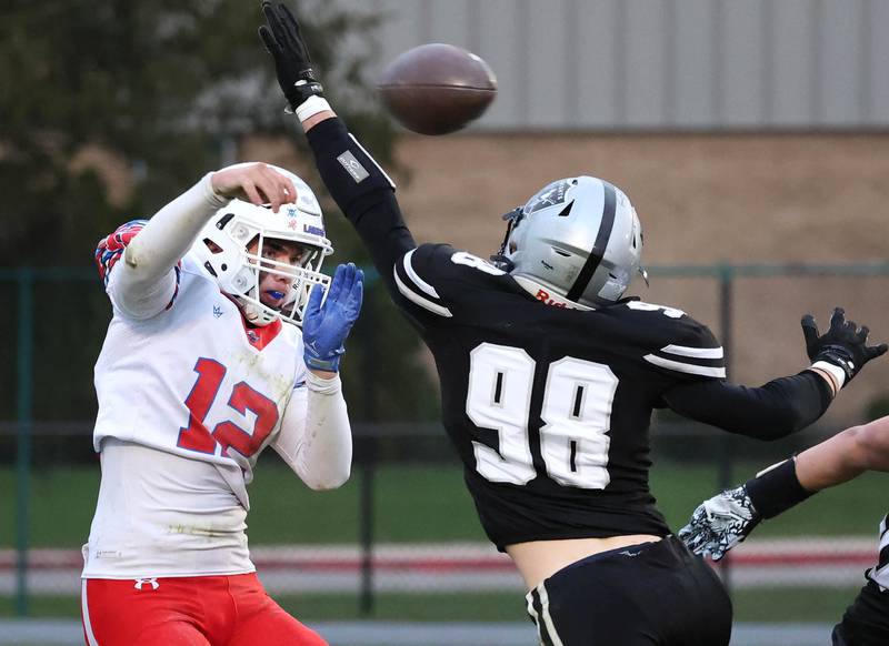 Lakes’ Ean Ankney gets a pass off just past the arm of Kaneland's Reiss Thompson Saturday, Nov. 1, 2025, during their first round playoff game at Kaneland High School in Maple Park.