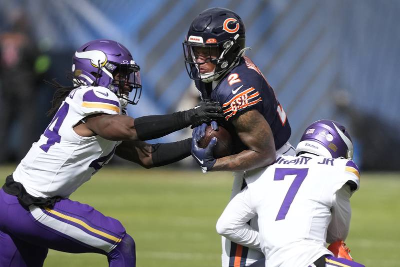 Chicago Bears wide receiver DJ Moore catches a pass from quarterback Justin Fields as Minnesota Vikings safety Josh Metellus (44) and Byron Murphy Jr. defend during a 2023 game in Chicago.