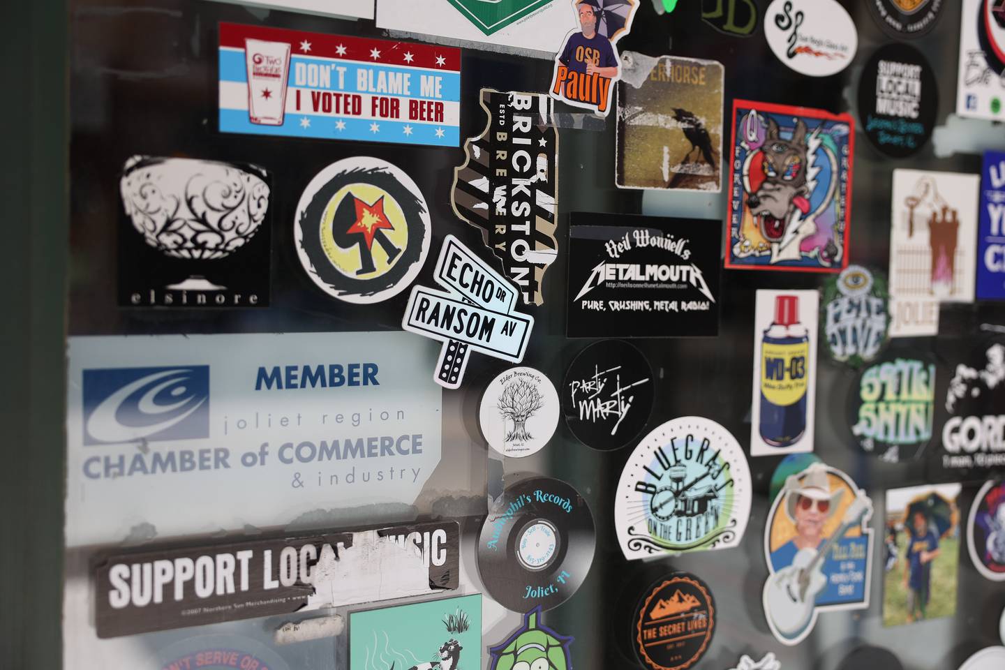 Nearly a hundred stickers of local bands that Mike Trizna has worked with are displayed on the entrance door at Chicago Street Pub located in downtown Joliet on Thursday May 30, 2024.