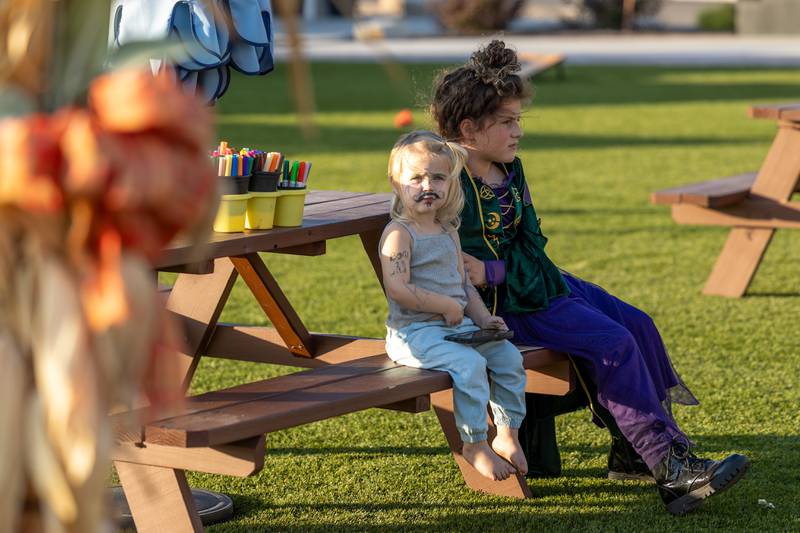 (from left) Oakley Baker and Vivian Carlson sit on a bench at the annual Witches Walk on Friday, Oct. 17, 2025, at the Market on Mill in Utica.