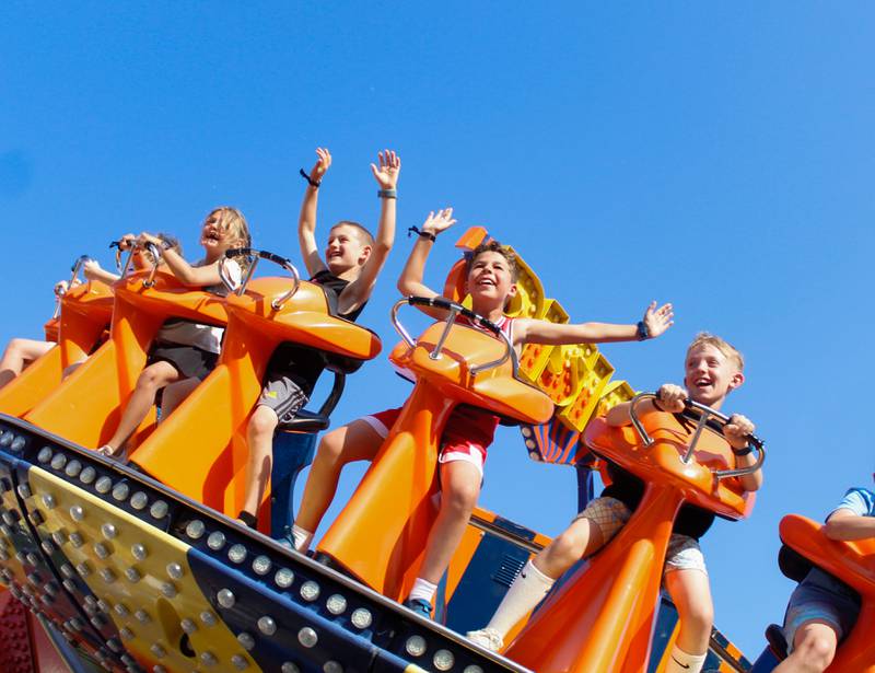 Kids wave their arms while riding the "Disko" ride, at the Downers Grove Rotary GroveFest on Thursday, June 19, 2025.