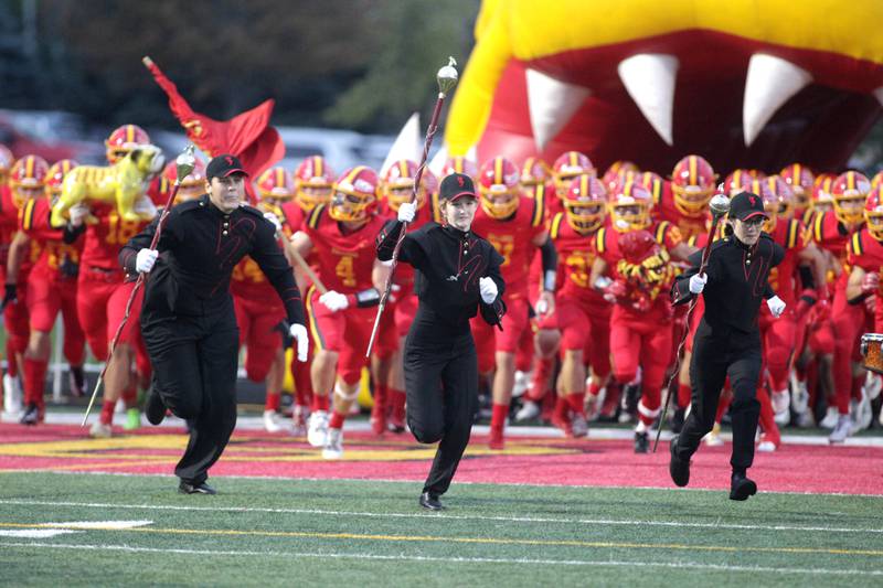 Batavia High School Marching Band drum majors lead the football team onto the field before their home game against Wheaton North on Friday, Sept. 22, 2023.