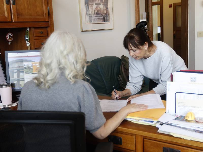 Wendy Barker, who is running for the Woodstock City Council, signs her candidate filing papers as Jane Howie, an executive assistant and election official with the city of Woodstock, on Monday, Nov. 28, 2022, at City Hall. Monday was the last day to file for the cities of Woodstock and Crystal Lake.