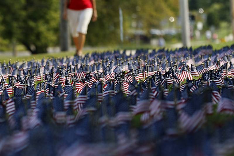 Attendees arrive passing a Field of Honor during a Patriots Day remembrance for the 20th anniversary of the terrorist attacks of 9/11 on Saturday, Sept. 11, 2021 at Union Cemetery in Crystal Lake.