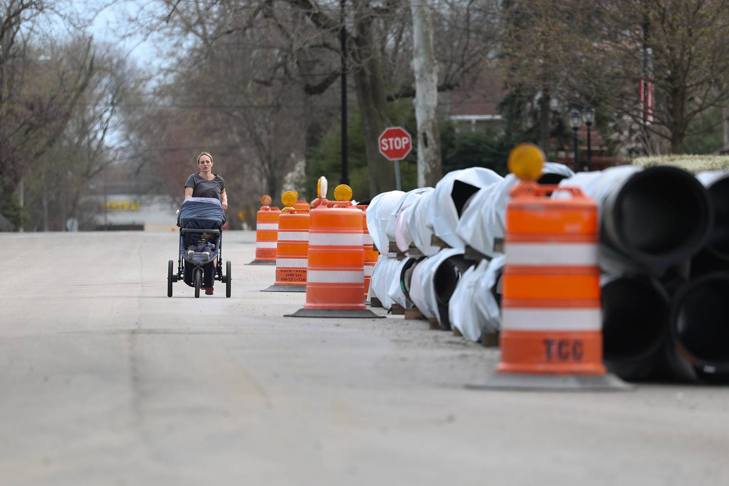 A mother jogs around a stack of pipes along North Williams St. on Wednesday, April 10, 2024 in Joliet.