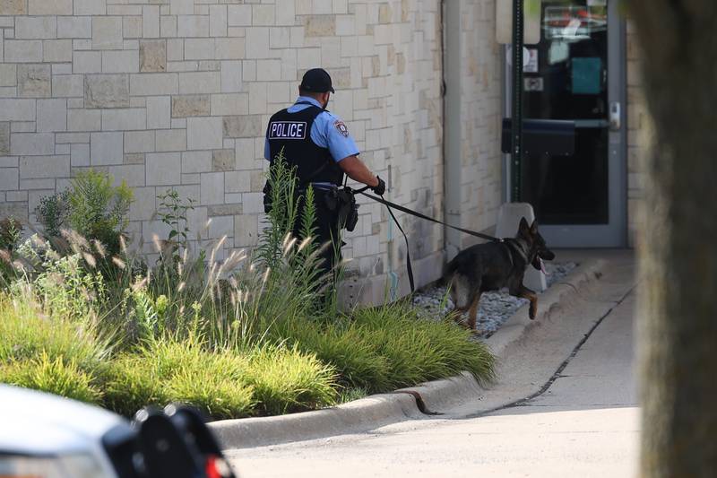 A K9 unit does a perimeter check at the Black Road Branch Library after a bomb threat at that location on Thursday, Sept. 14, in Joliet.
