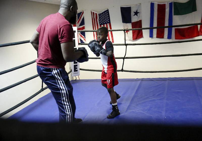 Joseph "Jo Jo" Awinongya, spars with his father, Joseph, during a workout last winter at the Chicago Sports & Fitness Club in Joliet.