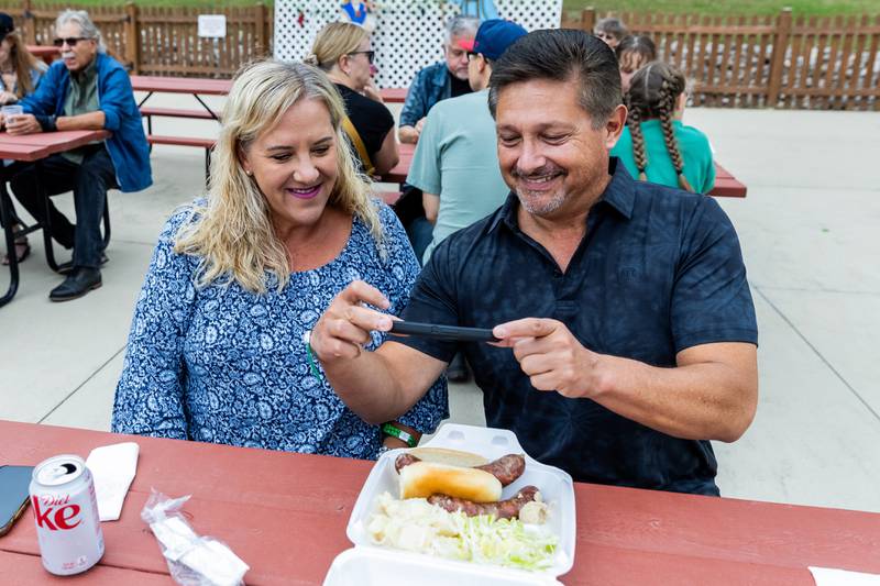 Monica Gesiakowski (New Lenox) and Dan Potochnic (Shorewood) snap a photo of their smokies and sides at the Slovenian Grape Harvest Festival on Sept. 29, 2024.