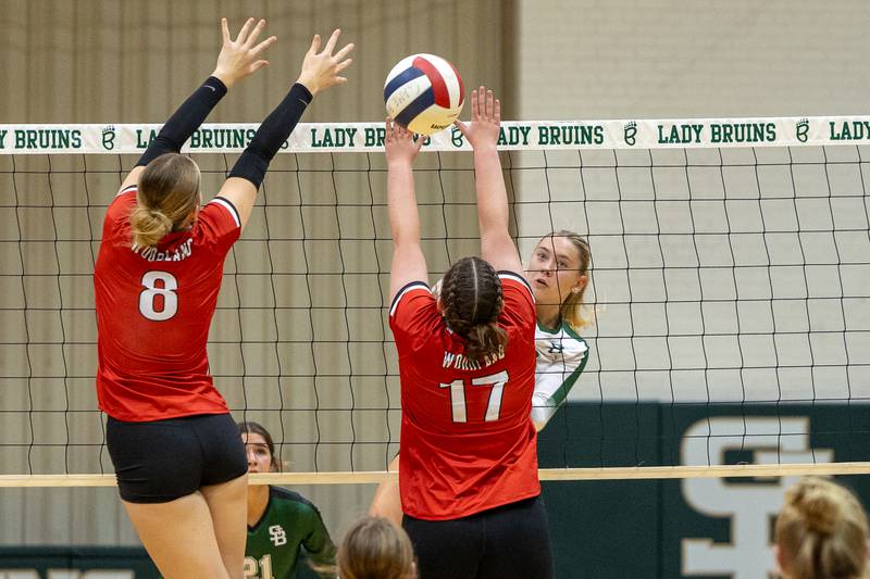 Grace Longmire (8) of Woodland and teammate Adrianna Kuehn (17) let ball slip through fingers as Nelle Potthoff of St. Bede sends ball over net on Thursday, Sept. 11, 2025 at Abbot Vincent Gymnasium in Peru.