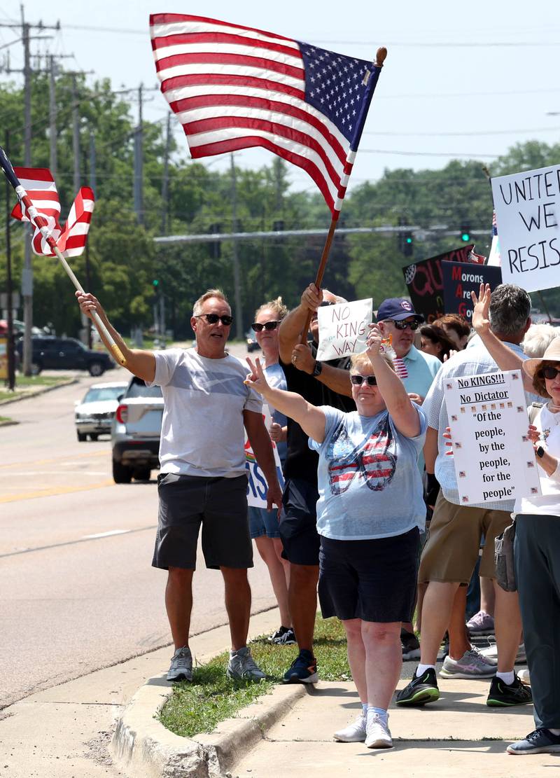 Protesters chant and wave flags along Sycamore Road Saturday, June 14, 2025, during a No Kings rally at Hopkins Park in DeKalb. The group was protesting the policies of President Donald Trump and his administration.