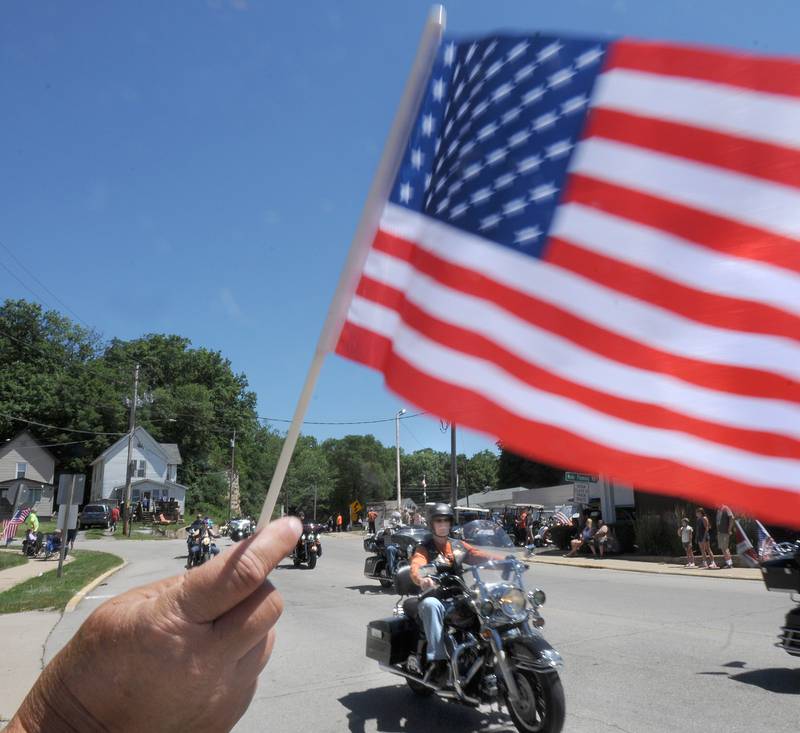 Marseilles residents wave flags and welcome thousands of motorcycle riders Saturday, June 18, 2022, as they arrive on Rutland Street for the Illinois Motorcycle Freedom Run.