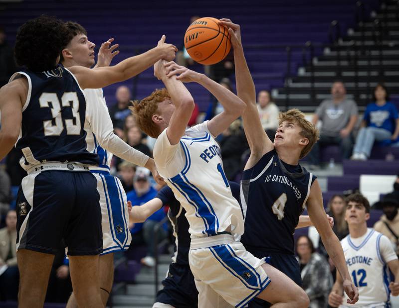 IC Catholic's Alex Simkowski, right, looks to grab a rebound over Peotone's Ethan McNeill, center, in the Thanksgiving tournament at Manteno High School on Monday, November 24, 2025.