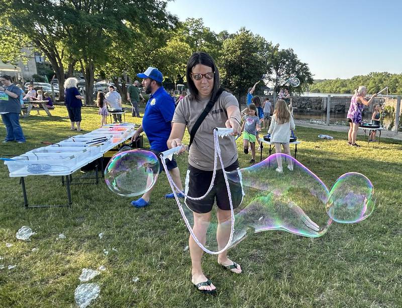 Mindy Nesemeier of Mt. Morris makes a large bubble with her kids at the River's Edge Farmers Market in Oregon on Thursday, June 19, 2025. The bubble fun was provided by "Bubble Guy" Jason Kollom, who was sponsored by the Oregon Public Library. The Farmers Market is held Thursday nights 5-7:30 p.m. at 123 N. 2nd St., in Oregon.