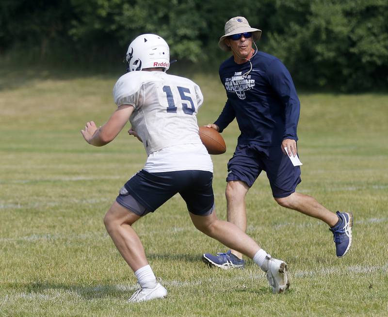 Cary-Grove’s Jake Hornok runs a pass pattern in front of coach Brad Seaburg during football practice Thursday, June 29, 2022, at Cary-Grove High School in Cary.