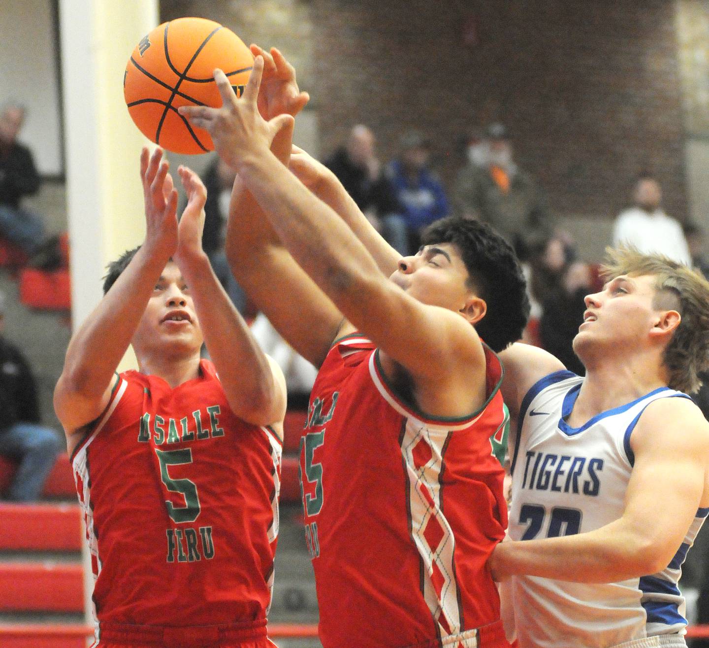 From left, La Salle-Peru's Erick Sotelo (5) and Andy Medina (45) fight Princeton's Arthur Burden for a rebound on Friday, Nov. 29, 2024, at Kingman Gym.