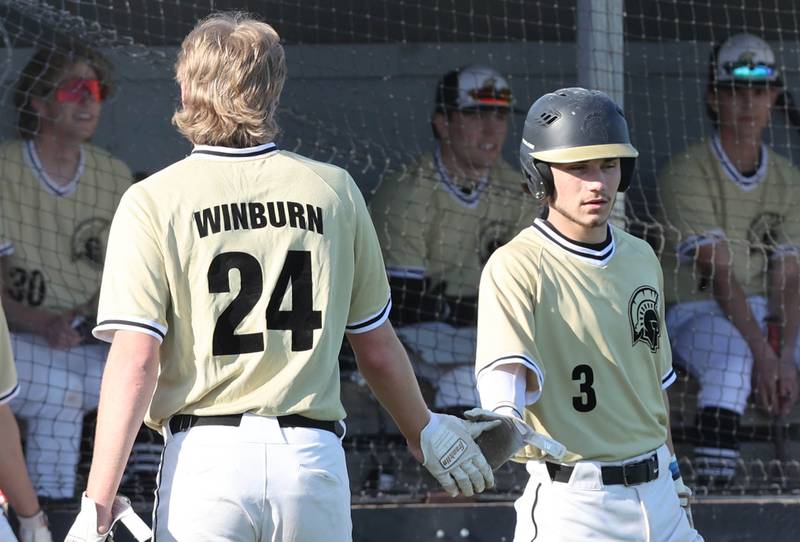 Sycamore's Lucas Winburn gets congratulated by Hunter Britz after scoring a run during their game against Kaneland Thursday, May 4, 2023, at Kaneland High School.