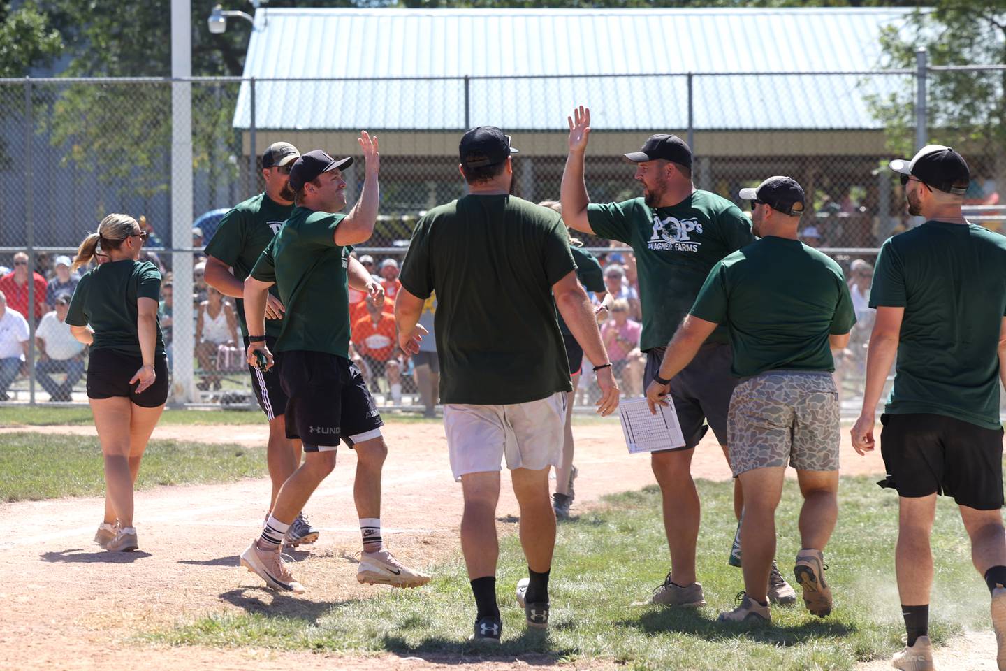 Brock Pfeiffer, left, runs to high five teammate Justin Ruckman to celebrate his walk-off home run to win the game during the 104th annual Herscher Labor Day Celebration on Monday, Sept. 1, 2025. The Pop's Wagner Farms team, composed of Herscher area family and classmates, would finish third on Championship day.