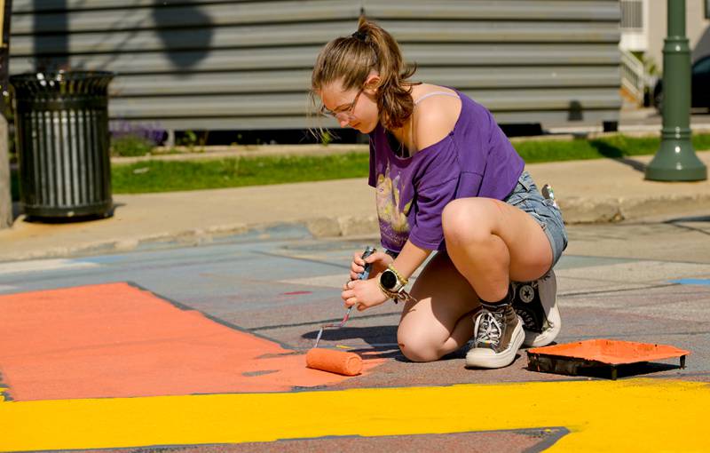 Tessa Muenz, 17 of St. Charles rolls out some orange paint inside the multi colored star themed mural during the St. Charles Art CouncilÕs ÒPaint the RiversideÓ in the intersection of Walnut and Riverside Avenues on Saturday, May 10, 2025 in St. Charles.