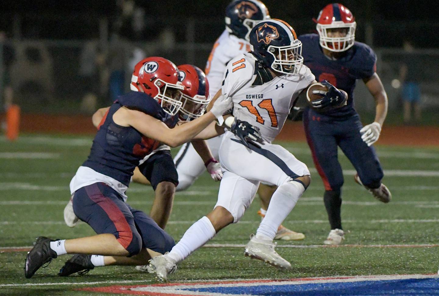 West Aurora's Fernando DeLeon (95) pulls on Oswego's Mark Melton (11) jersey as Melton gains some yards during third quarter of a game in Aurora on Friday, October 8, 2021.
