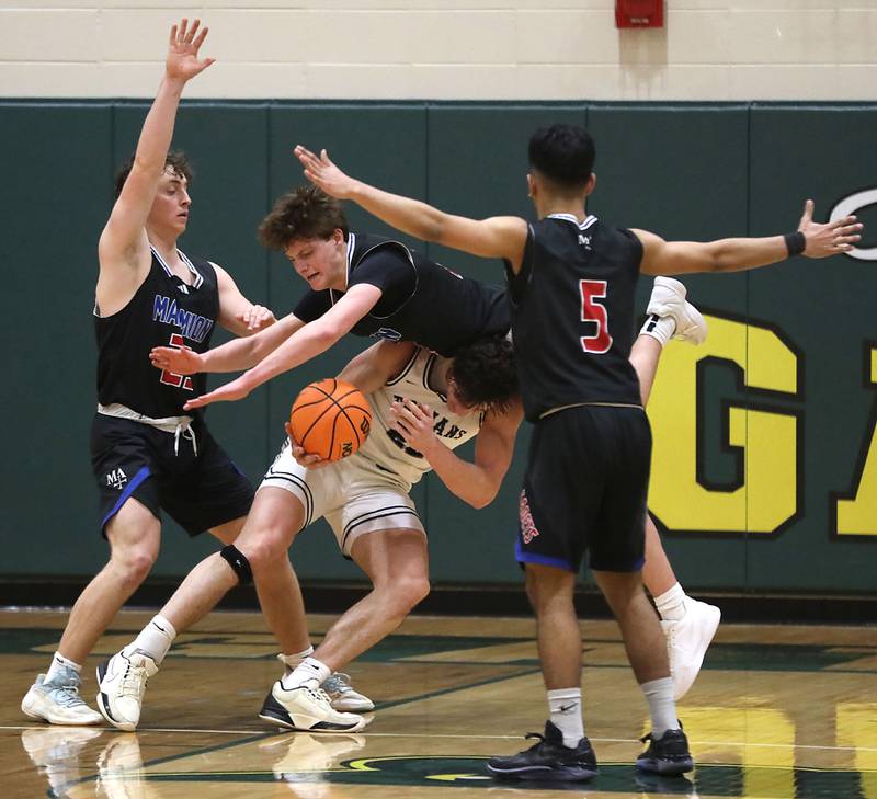Cary-Grove's Adam Bauer has Marmion's Colin McEniry land on him as the tries to drive to the basket between Marmion's Kadin Qadri (left) an dMarmion's Ali Tharwani (right) during an IHSA Class 3A Crystal Lake South Regional boys basketball semifinal game on Wednesday, February, 25, 2026, at Crystal Lake South High School.