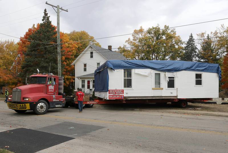 A house is backed into place Tuesday, Oct. 22, 2024, at its new location on Pleasant Street in Dekalb. The home was moved from the DeKalb County History Center property in Sycamore by Devooght House Movers and Habitat For Humanity for Heaven Allen and her son who will be living in the home when it is completed.