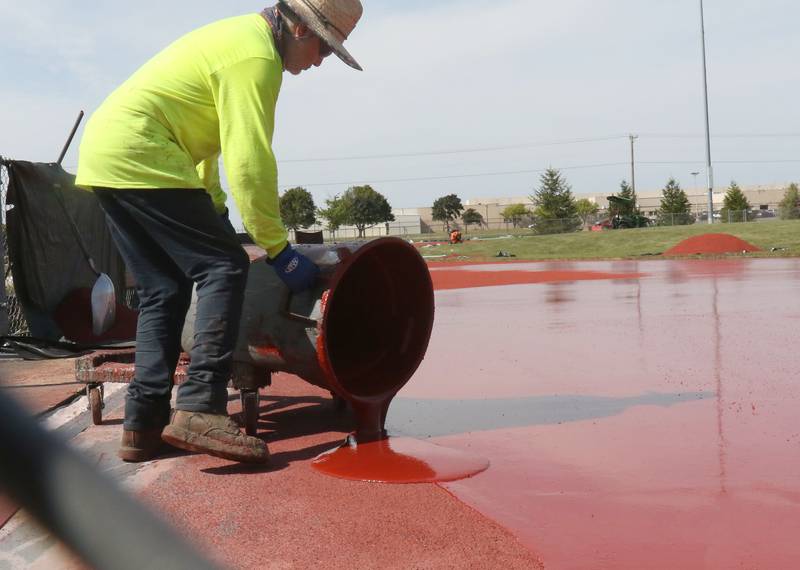 A worker with Track Surfaces Company in Elburn, dumps red dye onto the La Salle-Peru Township High School Track on Tuesday, Sept. 23, 2025 at the La Salle-Peru Township High School Athletic Complex in La Salle. Crews have been resurfacing the track for the past week. LaSalle-Peru Township High School Sports Complex will be closed to the public for approximately four weeks while the track undergoes resururfacing work. The track was first installed in 2014.