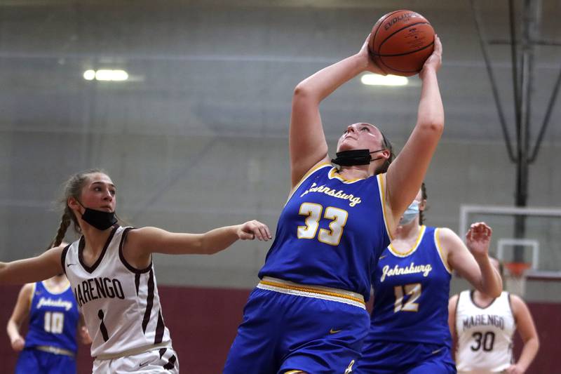 Johnsburg’s Molly Wetzel, right, snags a rebound as Marengo’s Emily Kirchhoff, left, keeps an eye on the ball during girls varsity basketball action Thursday night in Marengo.